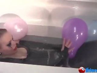 Lateks dressed gyz with balloons in a bathtub